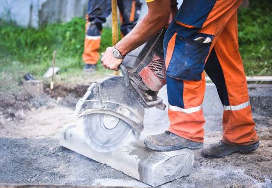 Construction worker cutting concrete paving stabs or metal