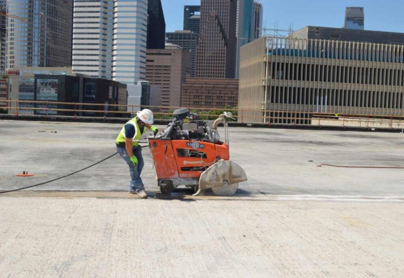 Construction worker operating a concrete saw on a rooftop slab in Texas & Louisiana
